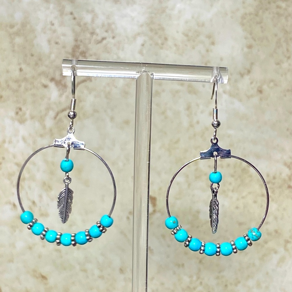 Silver tone hoop earrings with turquoise beads and feather charm